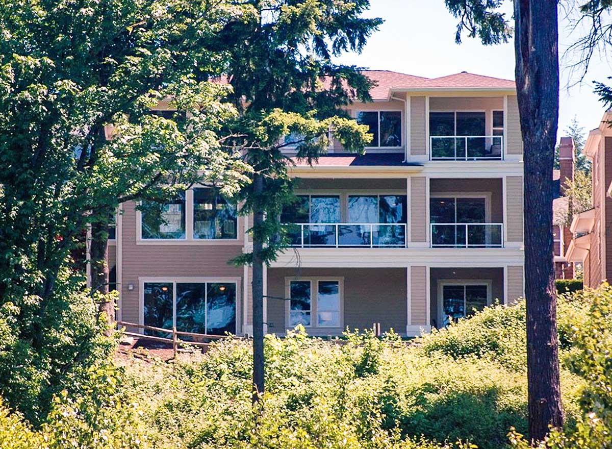 Exterior house plan with three stories, multiple balconies with glass railings, and large windows.