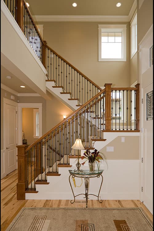 Interior view of a two-story foyer with a curved staircase featuring wood railings and ornate metal balusters.