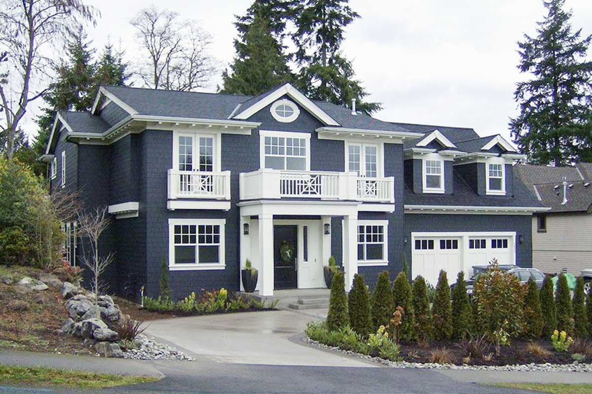 Two-story Modern Farmhouse exterior with a prominent front porch, dual second-story balconies, dormers, and a three-car garage.