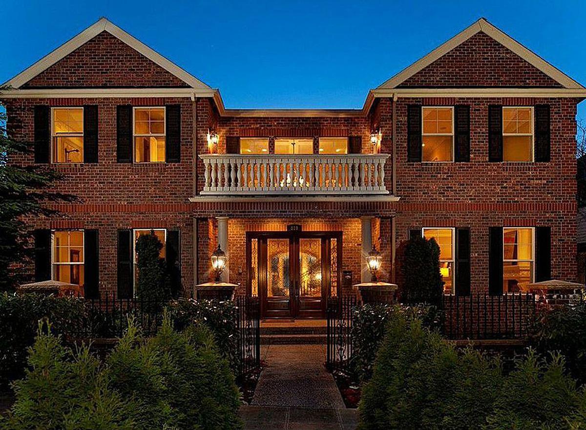 Two-story brick house plan with symmetrical gables, central second-story balcony, and prominent double front doors.
