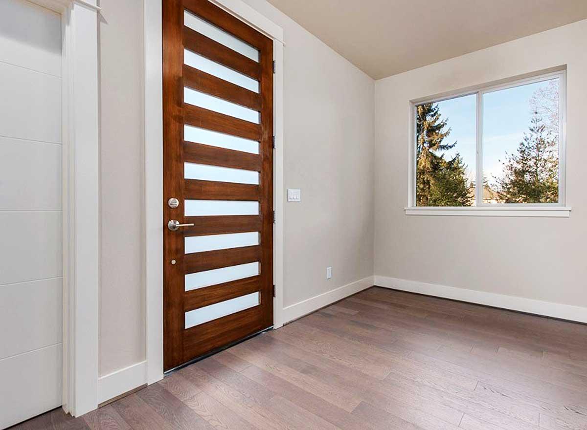 Interior view of a room with a modern wooden door featuring horizontal glass panes and a large picture window.