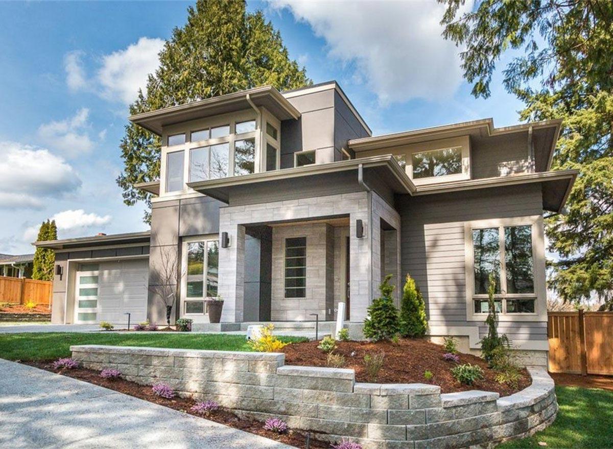 Modern house plan exterior with geometric rooflines, stacked stone pillars, and large windows.
