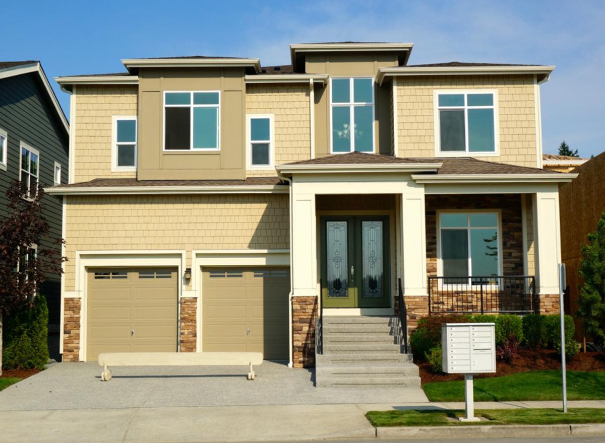 House plan exterior: Two-story home with dual garage doors, covered porch entry with double doors, and prominent upper-level windows.