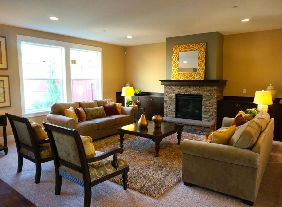 Living room with stone fireplace, dark wood cabinetry, plush seating, and large windows.
