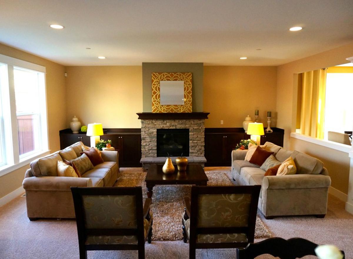 Great room with stone fireplace, two sofas, coffee table, and large windows.