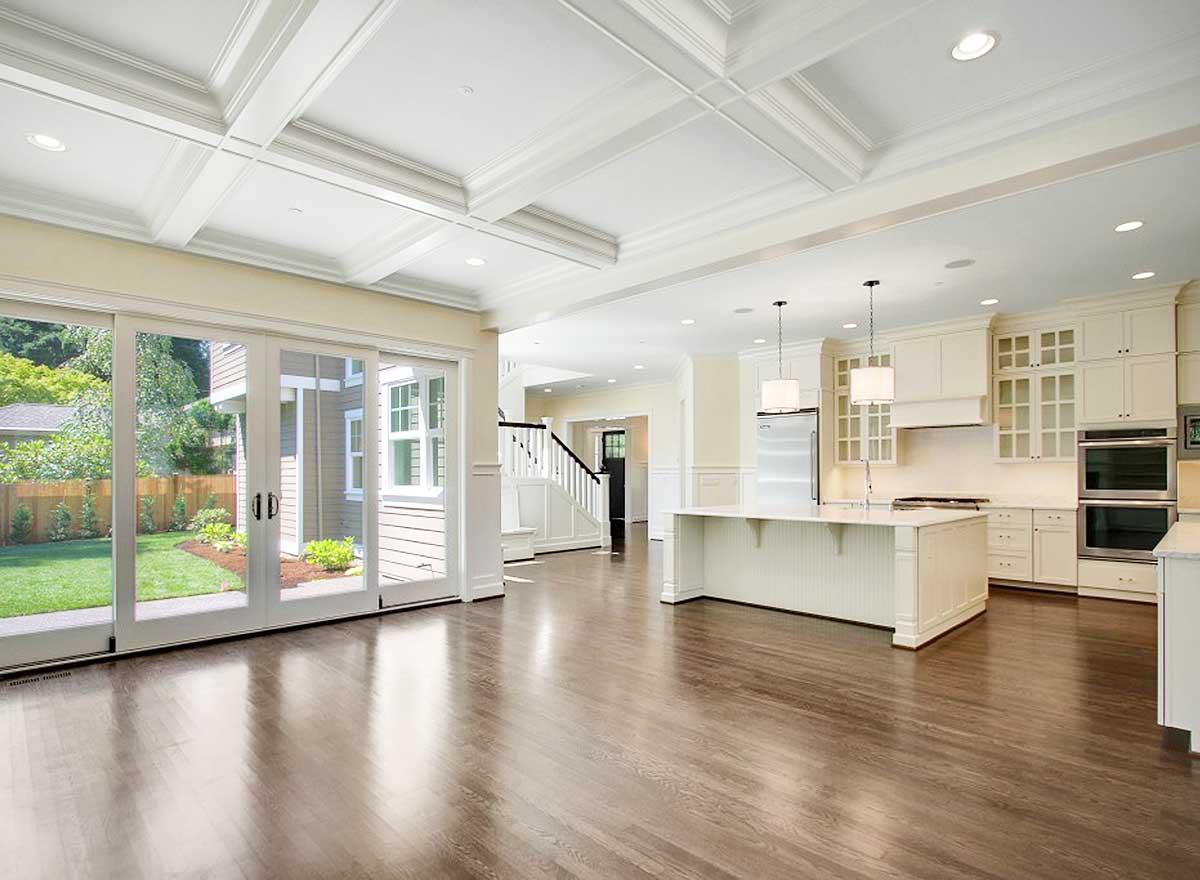 Open concept kitchen and great room with coffered ceiling, large island, and sliding glass doors to backyard.