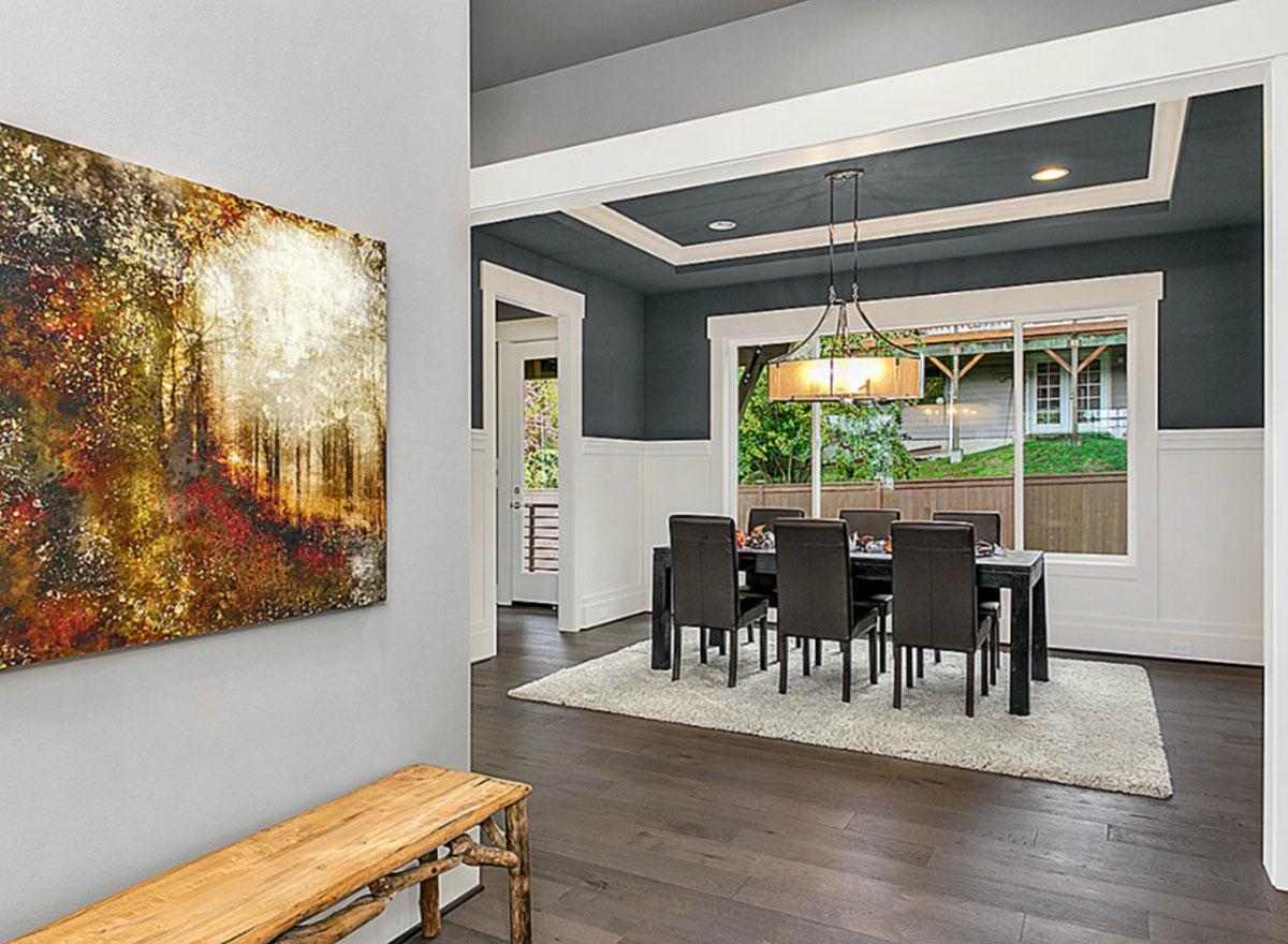 Dining room with dark wood floors, a rectangular table with chairs, and a tray ceiling with modern chandelier.