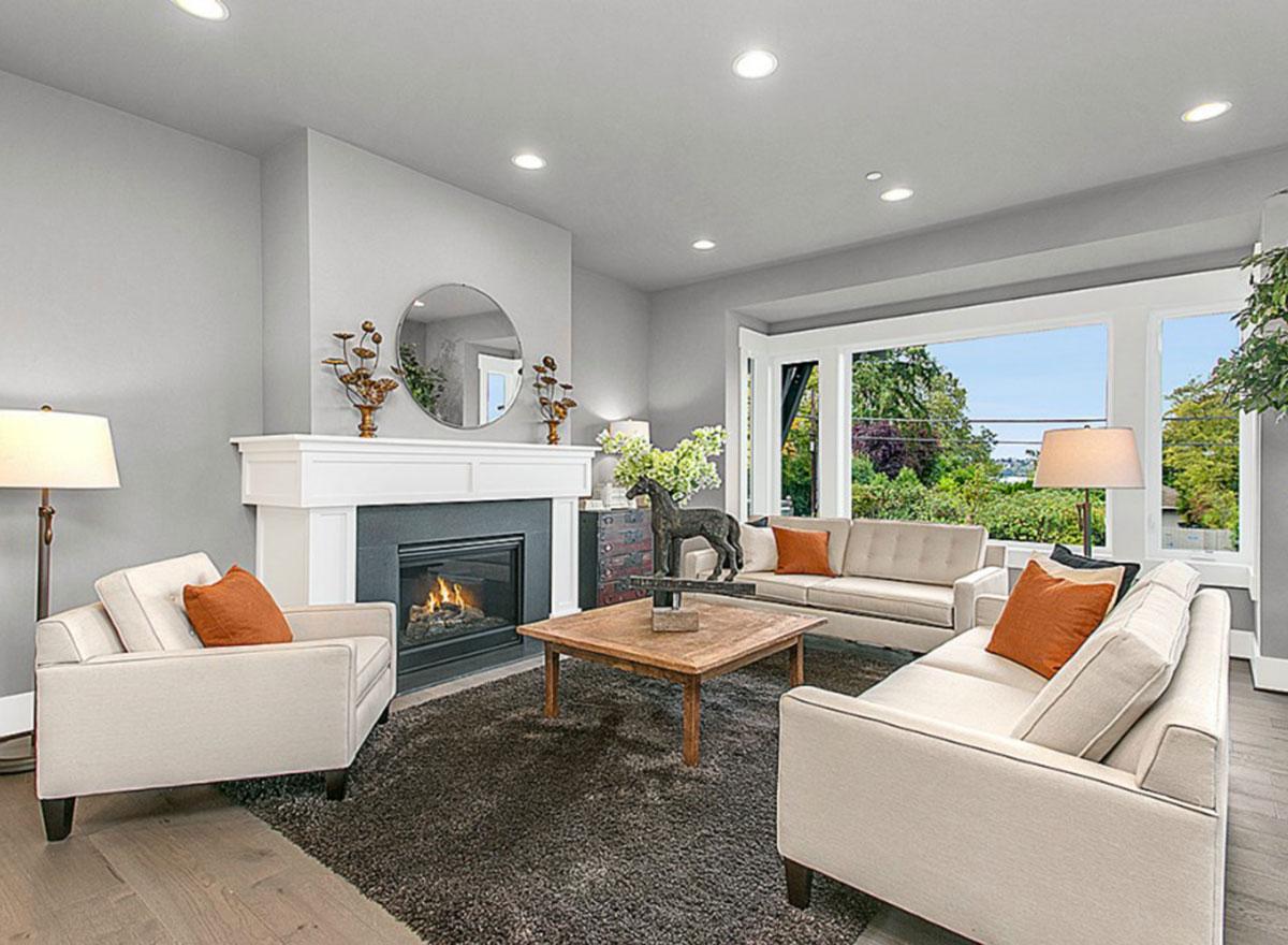 Living room with fireplace, large windows, and neutral-toned furniture.