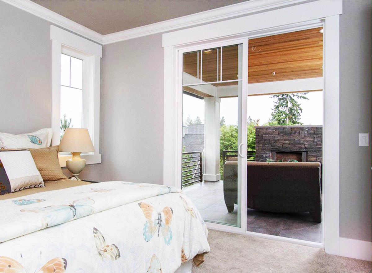 Bedroom with large sliding glass door opening to covered patio with stone fireplace and seating.