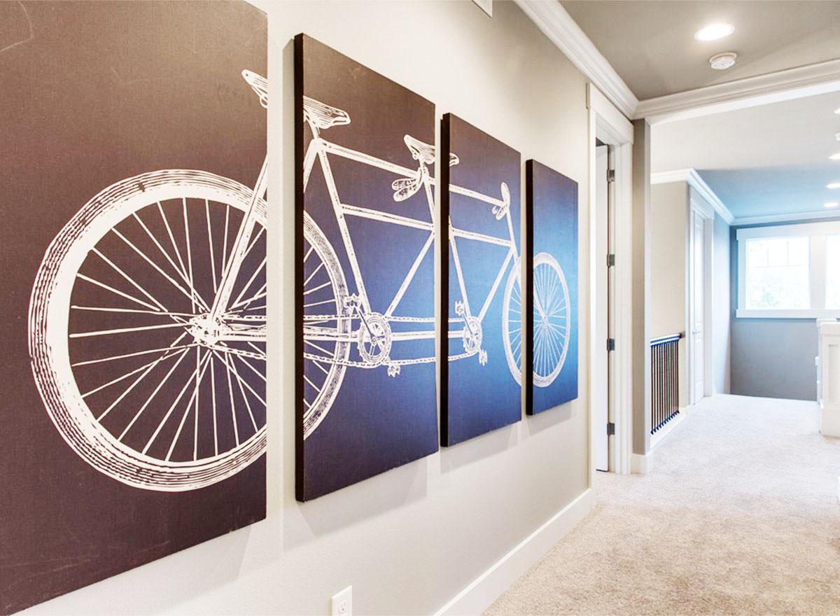 Hallway interior view with four dark blue wall panels featuring white bicycle line art and carpeted floor.