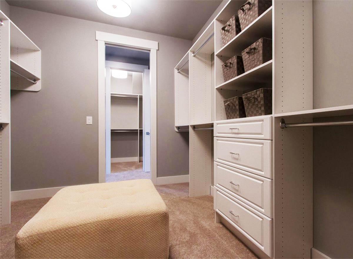 Walk-in closet with shelving, drawers, hanging rods, and access to an additional closet space.