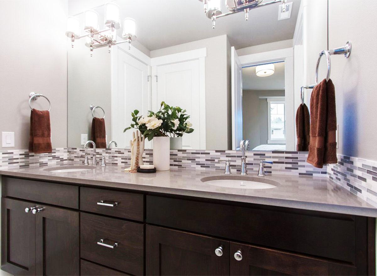 Bathroom vanity with double sinks, dark wood cabinets, mosaic tile backsplash, and chrome fixtures.