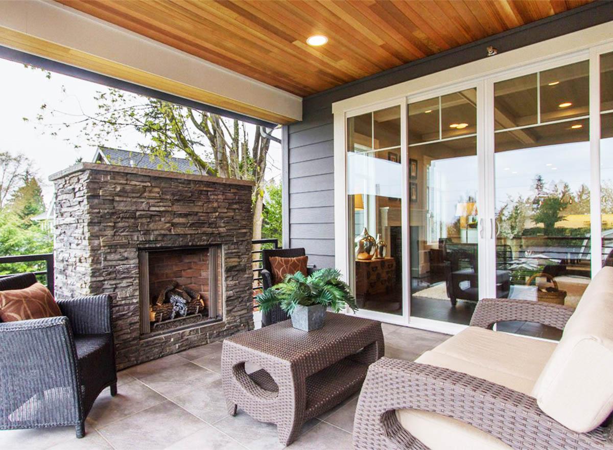 Covered patio with stone fireplace and sliding glass doors leading to interior living space.