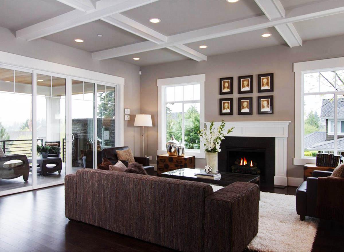 Interior rendering of a great room with coffered ceiling, fireplace, large sliding glass doors, and seating.