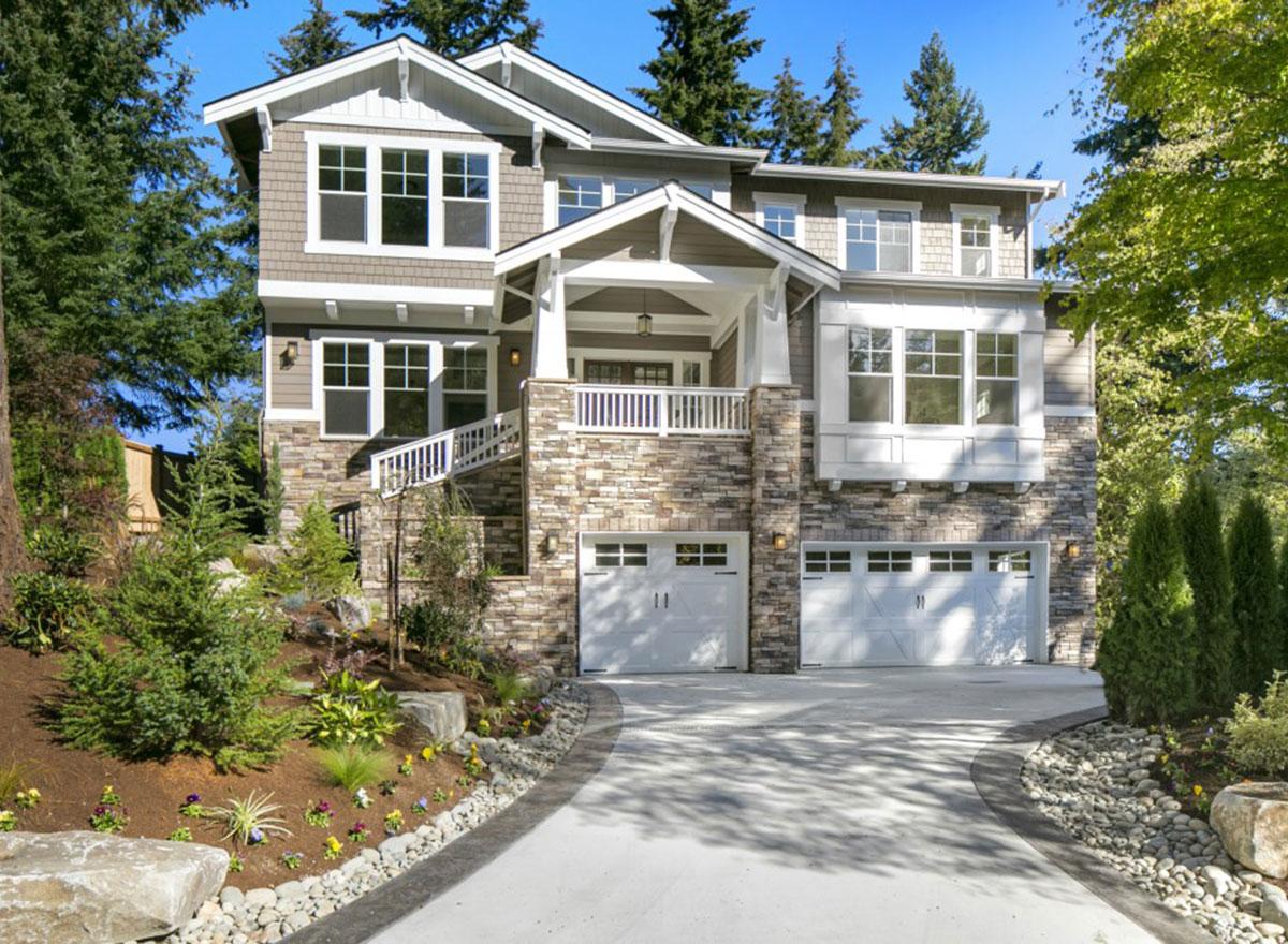 Craftsman style house plan exterior with stone and shingle siding, multiple gables, and a three-car garage.