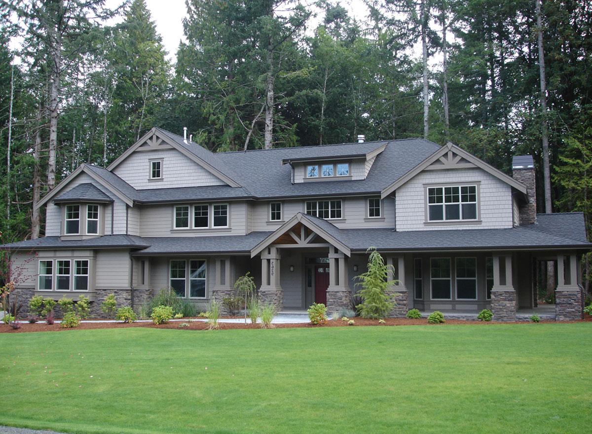 House plan exterior: two-story home with gabled dormers, stone-clad porch columns, and multiple rooflines.
