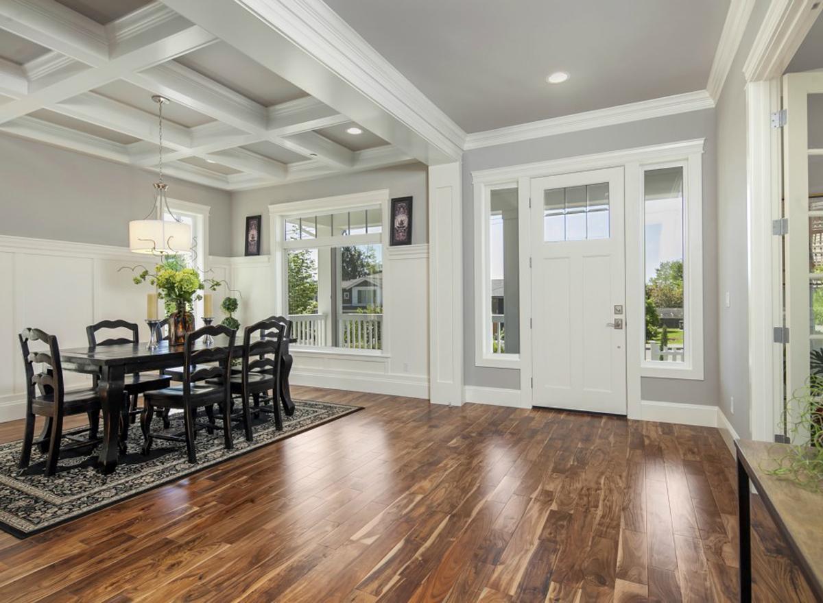 Interior view of dining area and entryway with coffered ceiling, wainscoting, and glass-paned double door.
