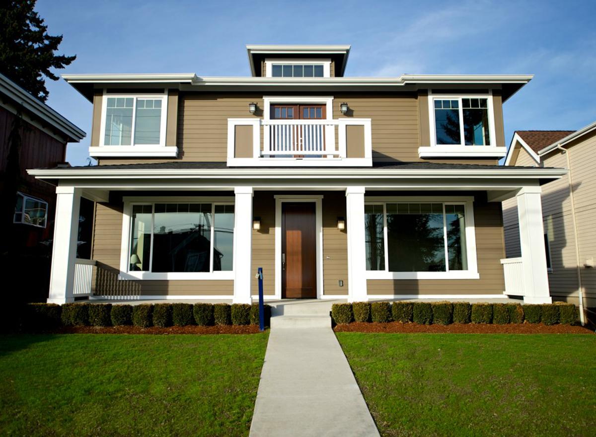House plan exterior: two-story home with hip roof, wrap-around porch, dormer, and upper balcony.