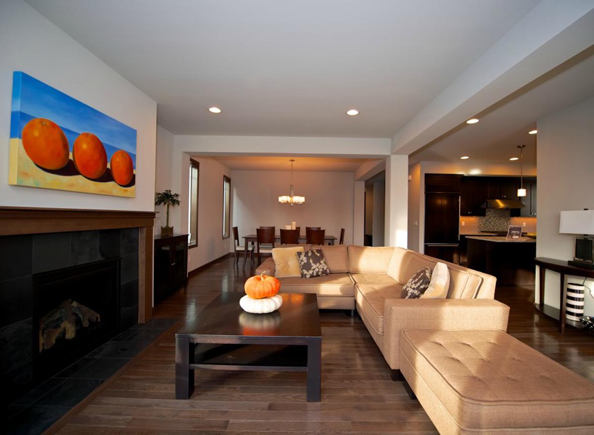 Living room with fireplace, sectional sofa, and open view to dining area and kitchen with dark cabinetry.
