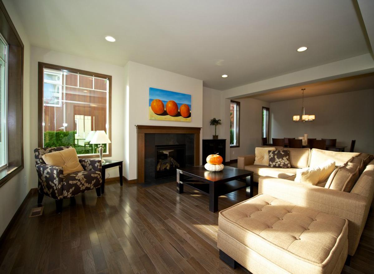 Living room interior with fireplace, coffee table, sectional sofa, patterned armchair, and view to dining room.