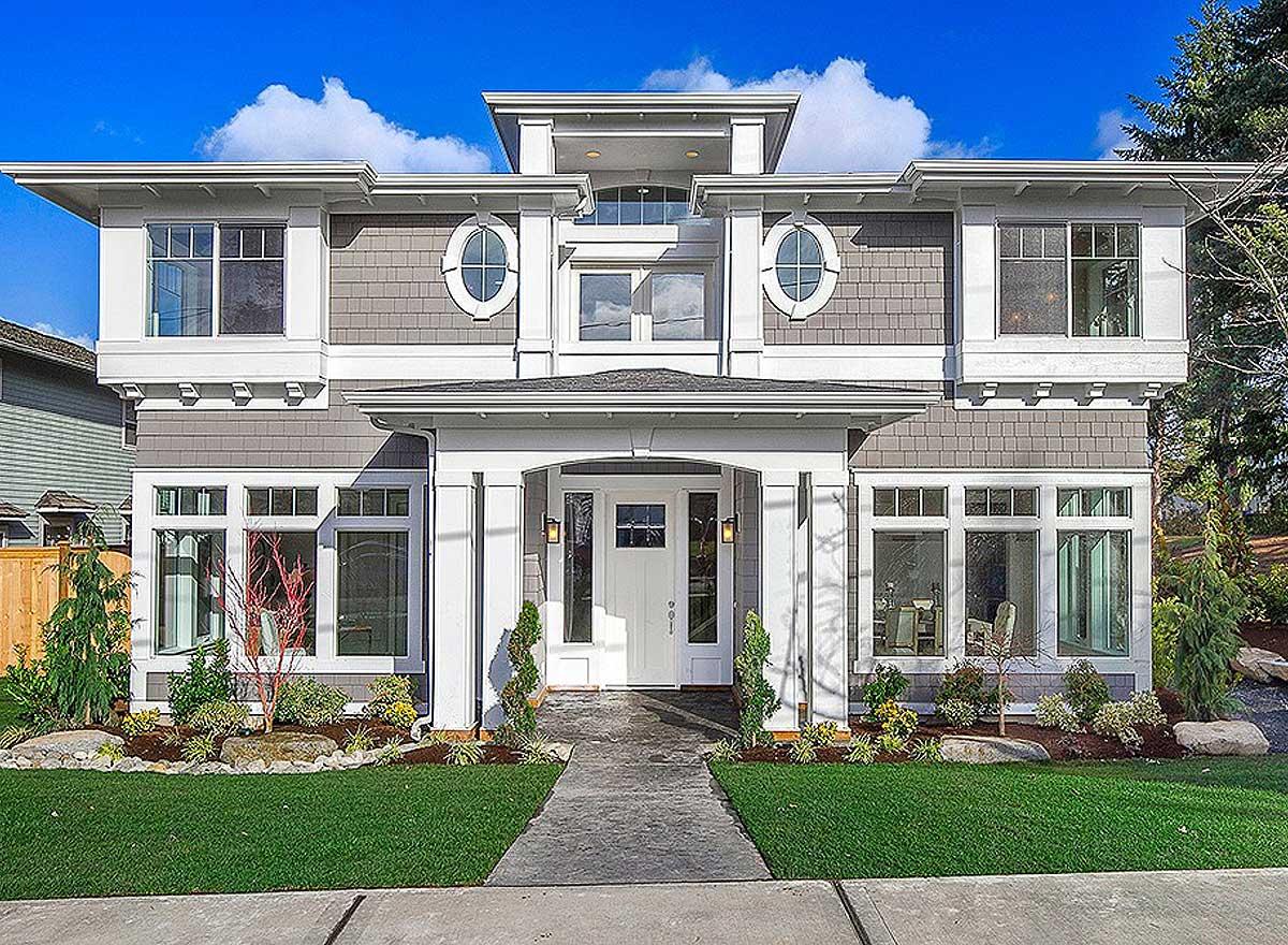 Two-story house plan exterior with layered rooflines, prominent portico, stacked windows, and oval dormers.