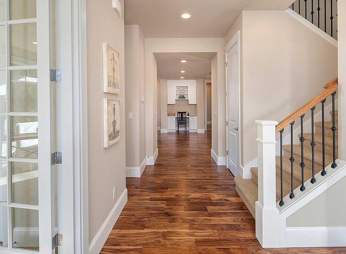 Interior hallway with hardwood floors, a built-in desk nook, and carpeted stairs with black balusters.