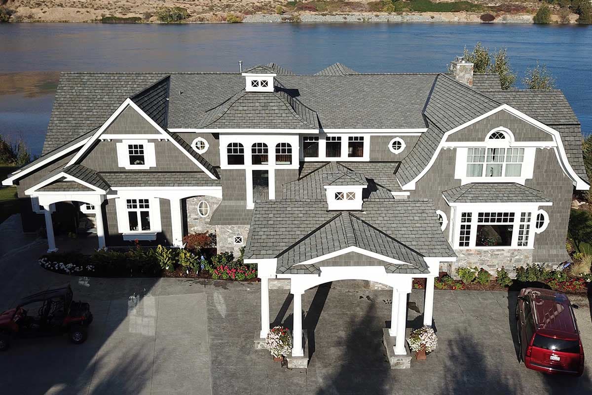 House plan exterior. Two-story with multiple gables, dormers, and a portico over the entrance. Features include an arched window and a gray roof.