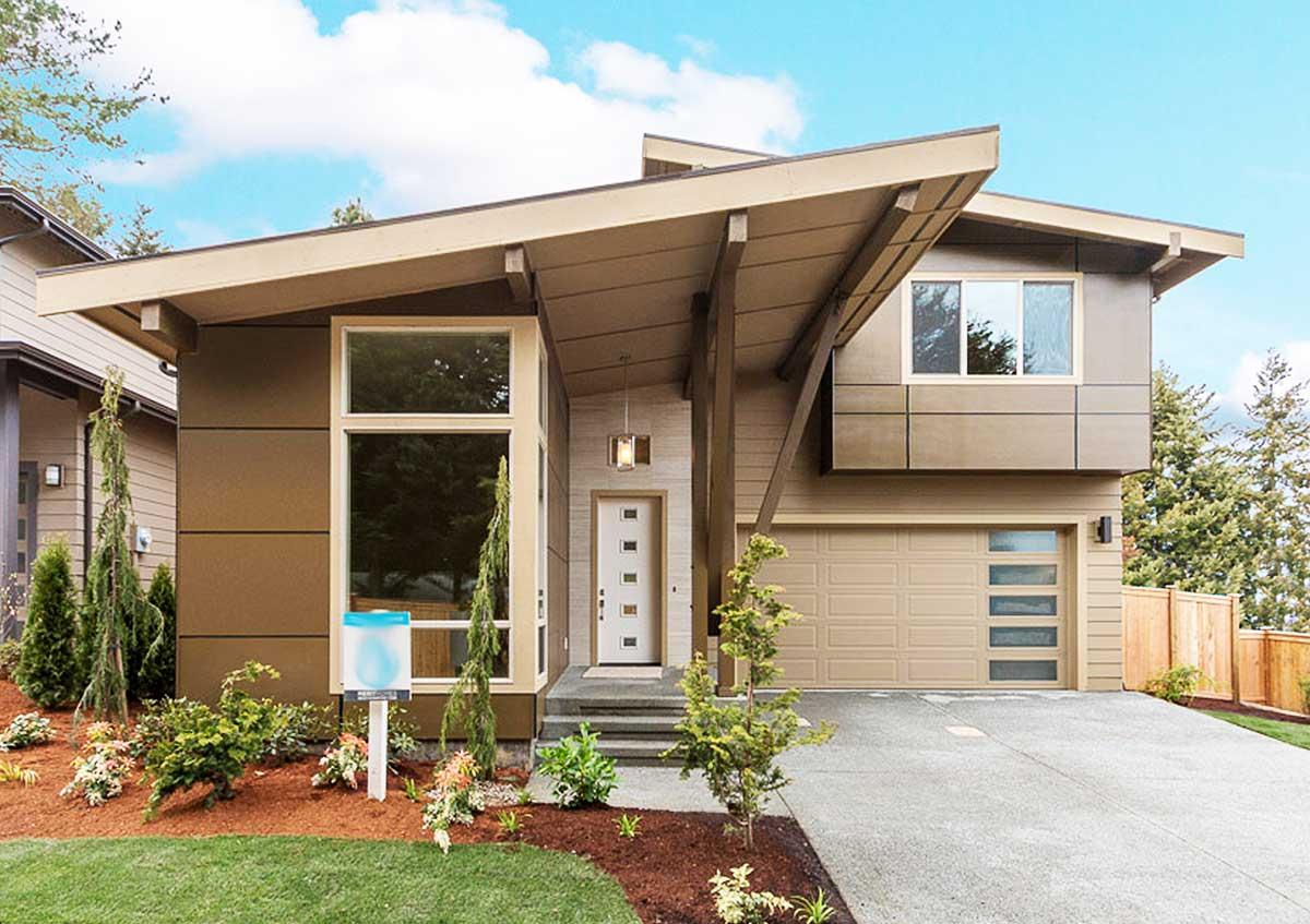 Modern house exterior with cantilevered upper story, angled rooflines, tall entry window, and sectional garage door.