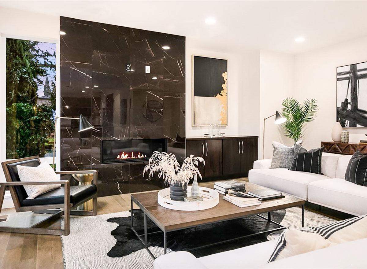 Great room with a modern linear fireplace, dark marble tile surround, white sectional, and large windows.
