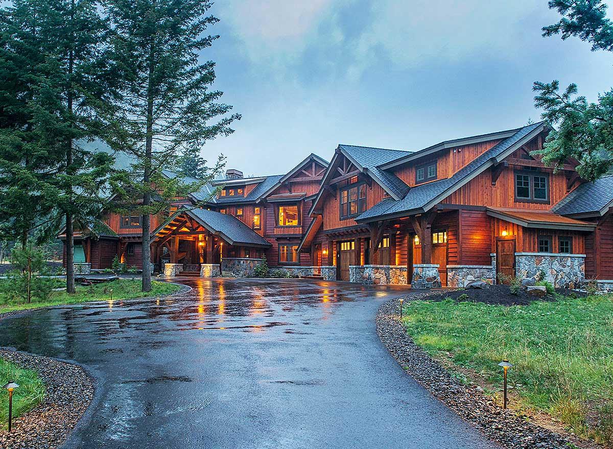 Mountain style house plan exterior with wood siding, stone accents, multiple gables, covered entry, and attached garages.
