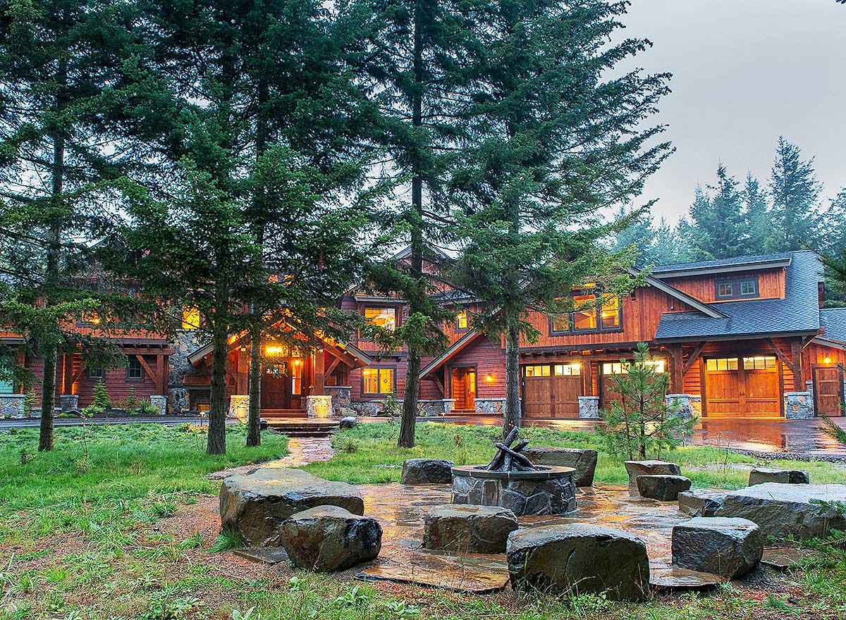 Rustic lodge-style house plan exterior with timber framing, multiple gables, stone accents, and a detached garage.