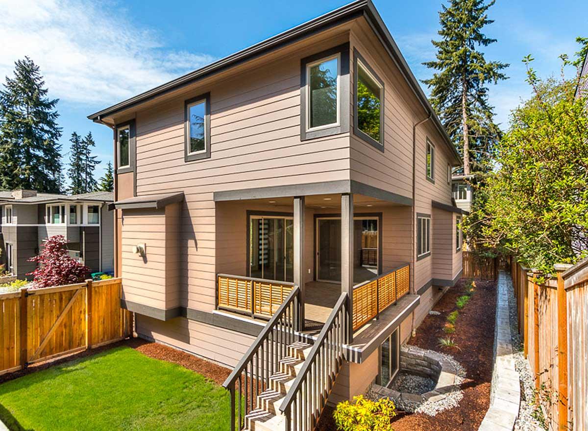 House plan exterior of a two-story contemporary home with a covered porch, deck, and prominent corner windows.