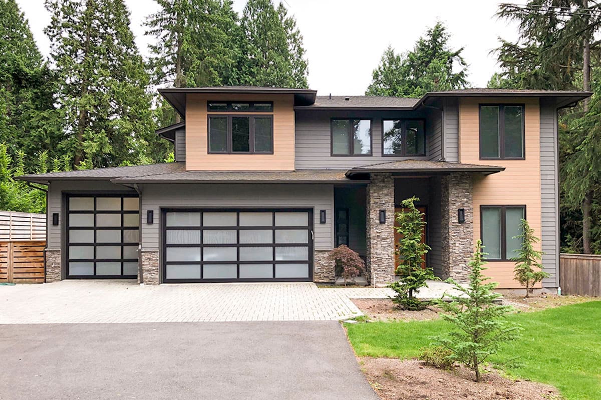 Modern two-story house plan exterior with stone accents, two frosted glass garage doors, and flat rooflines.