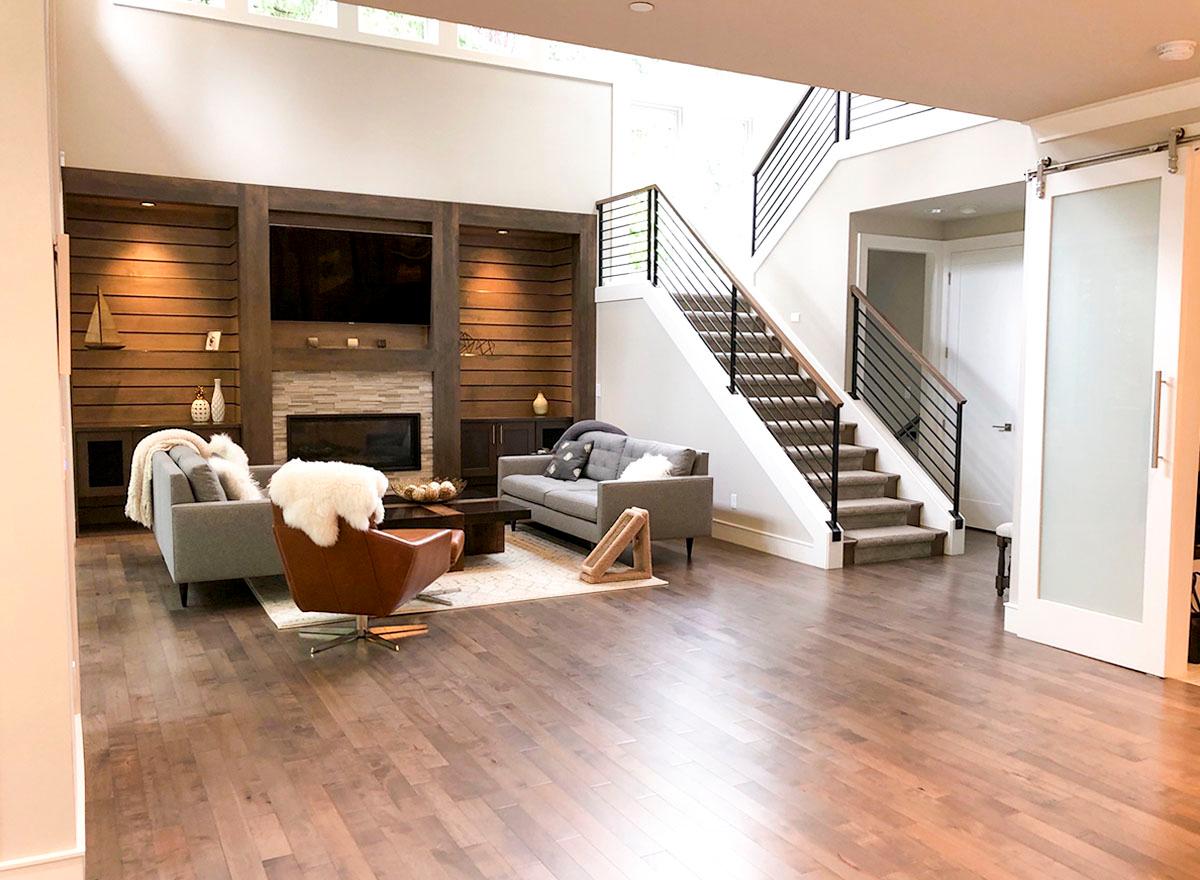 Great room with fireplace, built-in media center, and open staircase with modern railings.