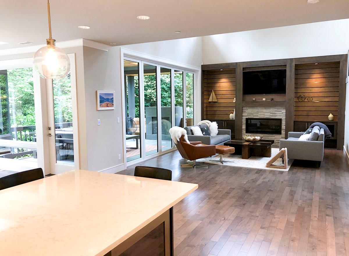 Open concept living room with fireplace, media wall, contemporary seating, and large sliding glass doors leading to an outdoor space.