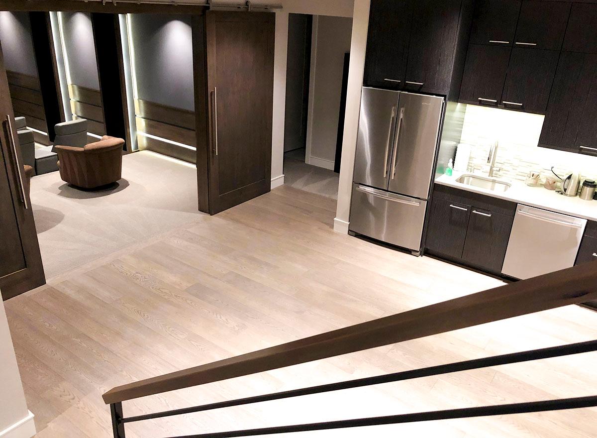 Interior view of a modern basement with stainless steel refrigerator, dark wood cabinets, and sliding barn doors.