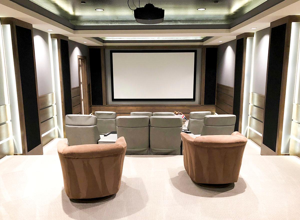 Home theater with tiered seating, projector screen, and accent lighting.