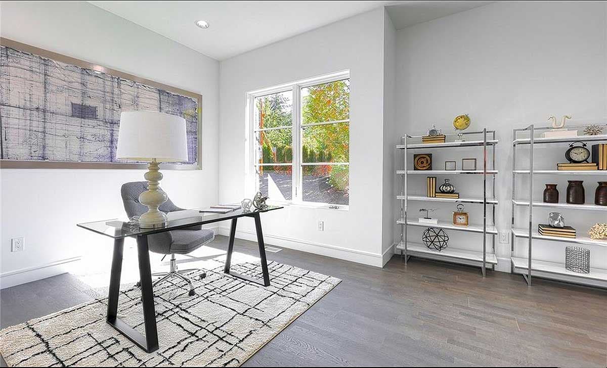 Office with glass desk, chair, large window, bookshelves, and abstract art.