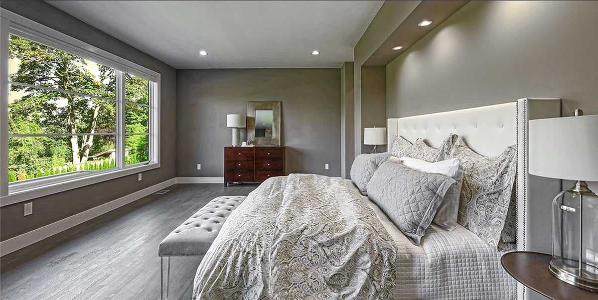 Modern bedroom with large picture window, upholstered headboard, and wood dresser.