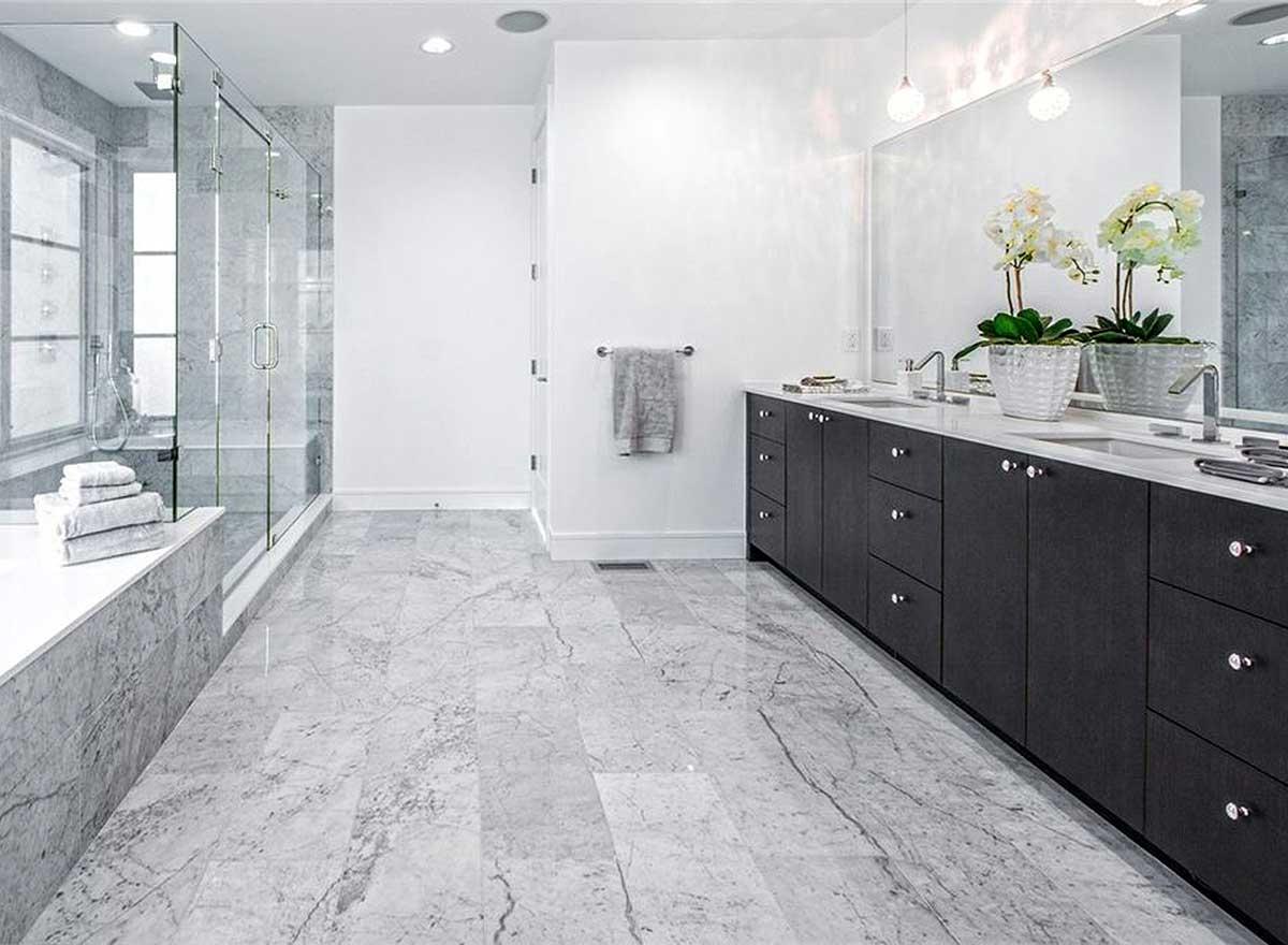 Modern bathroom with marble floor, freestanding tub, glass-enclosed shower, and double vanity with dark wood cabinets.