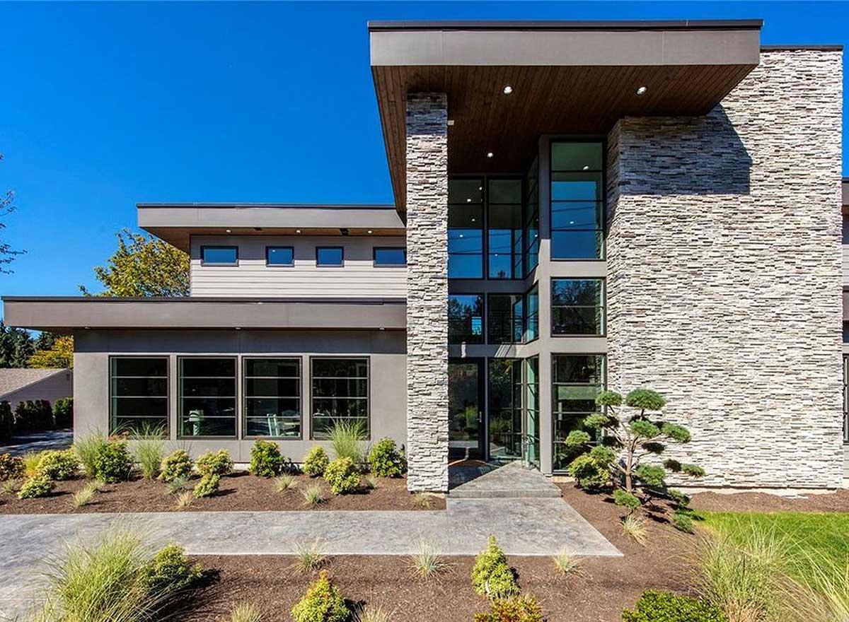 Modern house plan exterior with stacked stone facade, expansive glass entry, and flat rooflines.