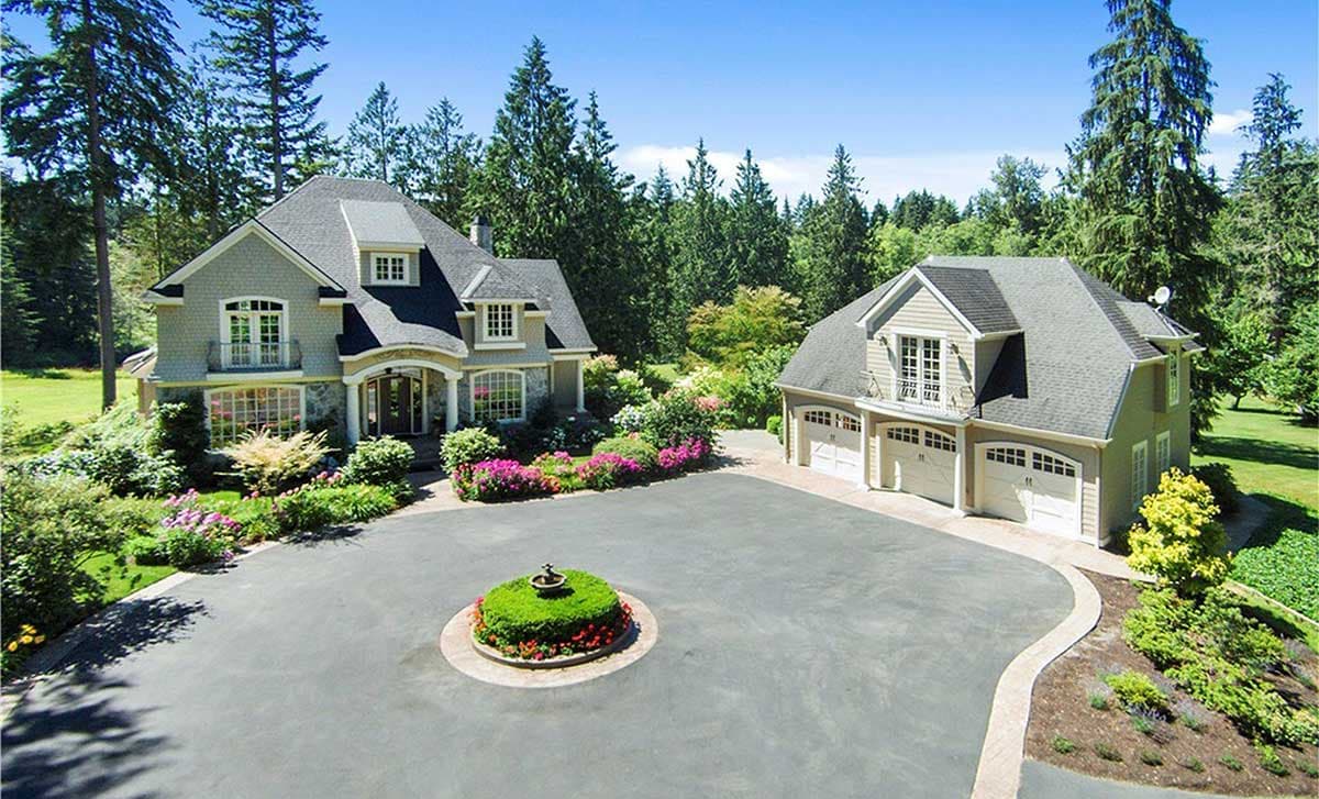 House plan exterior: Two-story home with gabled dormers, wraparound porch, and attached three-car garage.