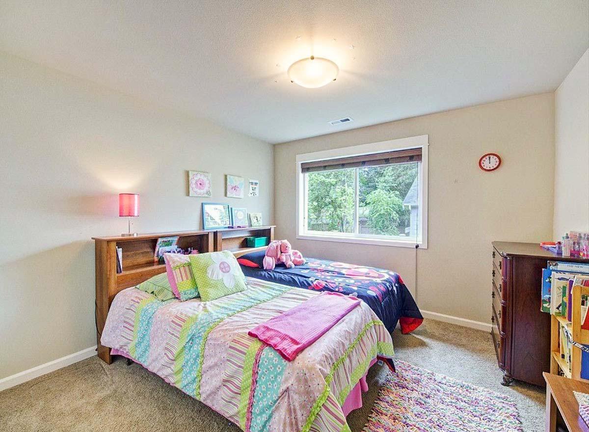 Bedroom with two beds featuring headboard shelves, a large window, and a dresser with a bookshelf.
