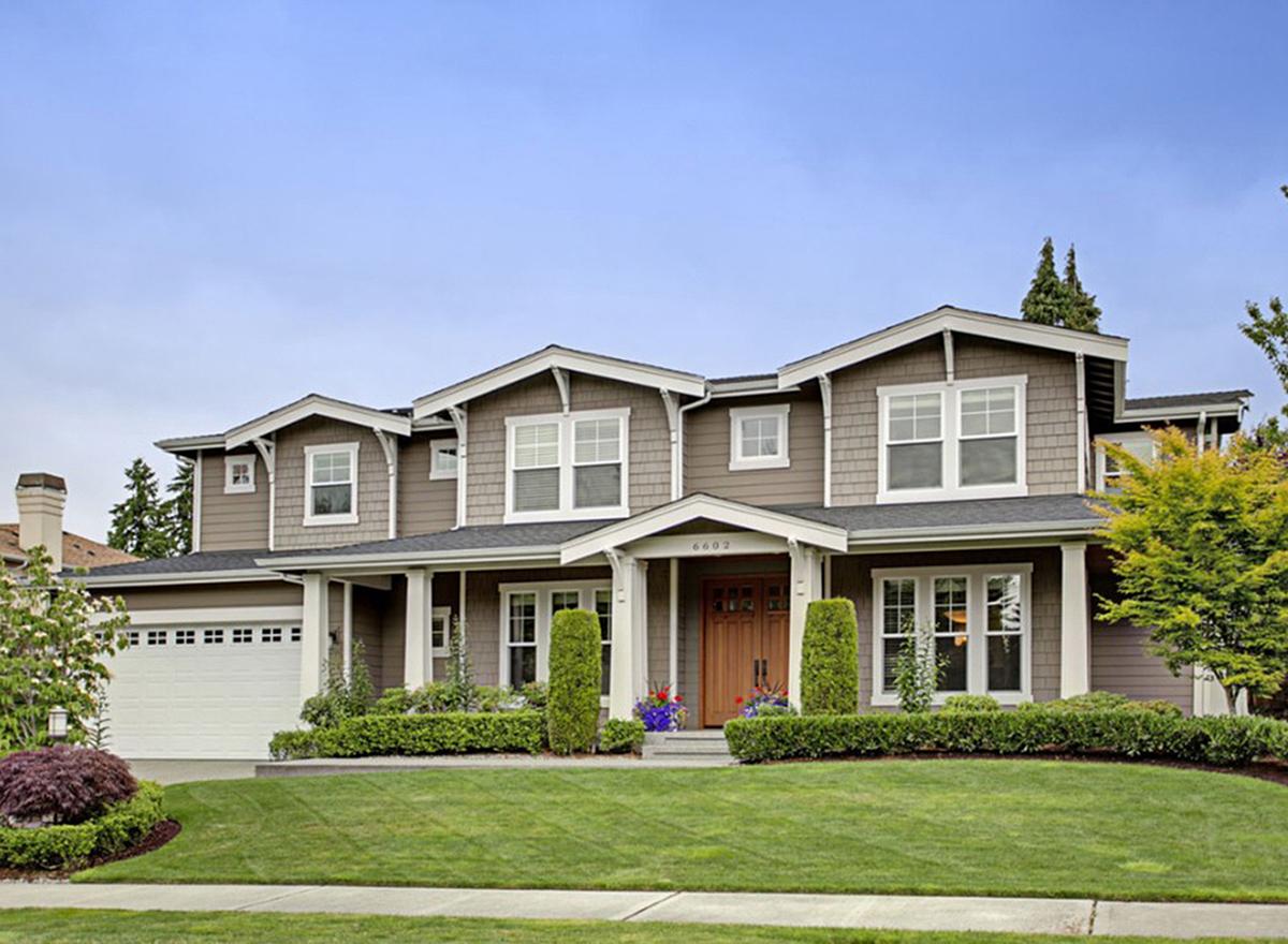 House plan exterior of a two-story home with a wrap-around porch, gables, dormers, and an attached garage.