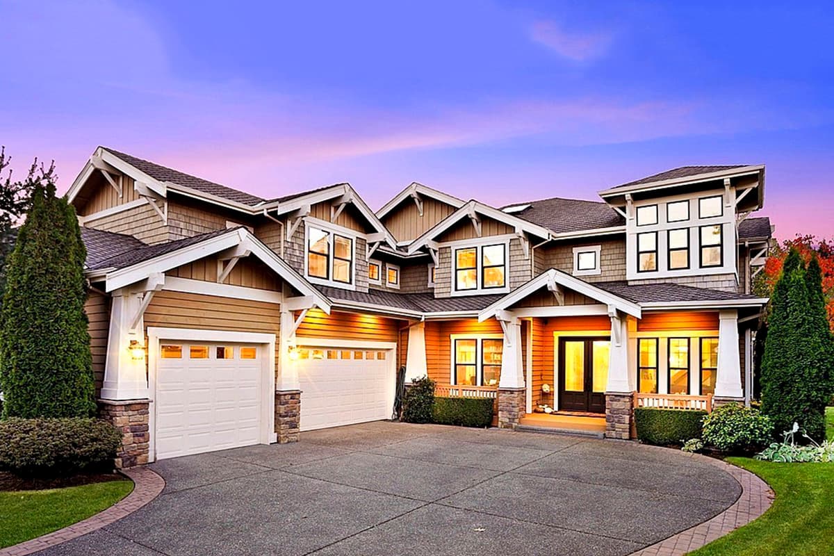 House plan exterior. Two-story Craftsman home with multiple gables, stone accents, and a covered front porch with columns. Features two garage bays.
