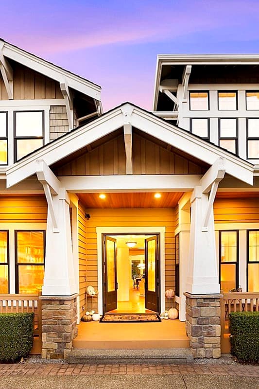 House plan exterior: Two-story modern home with prominent gables, stone-clad porch columns, and double entry doors.