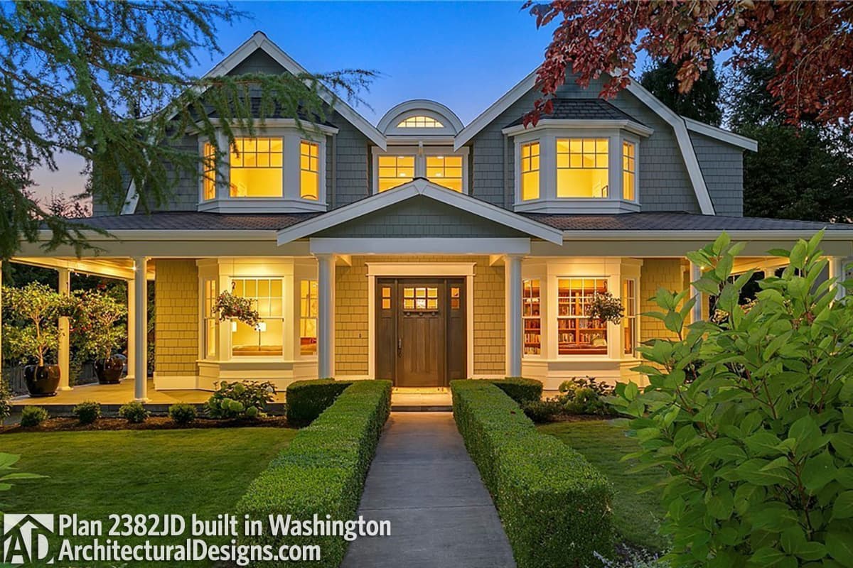 House plan exterior of a two-story home with bay windows, gabled dormers, a covered porch, and a prominent central entrance.