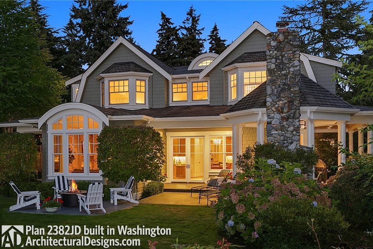 House plan exterior: Two-story home with gables, bay windows, arched window, stone chimney, and covered porch.