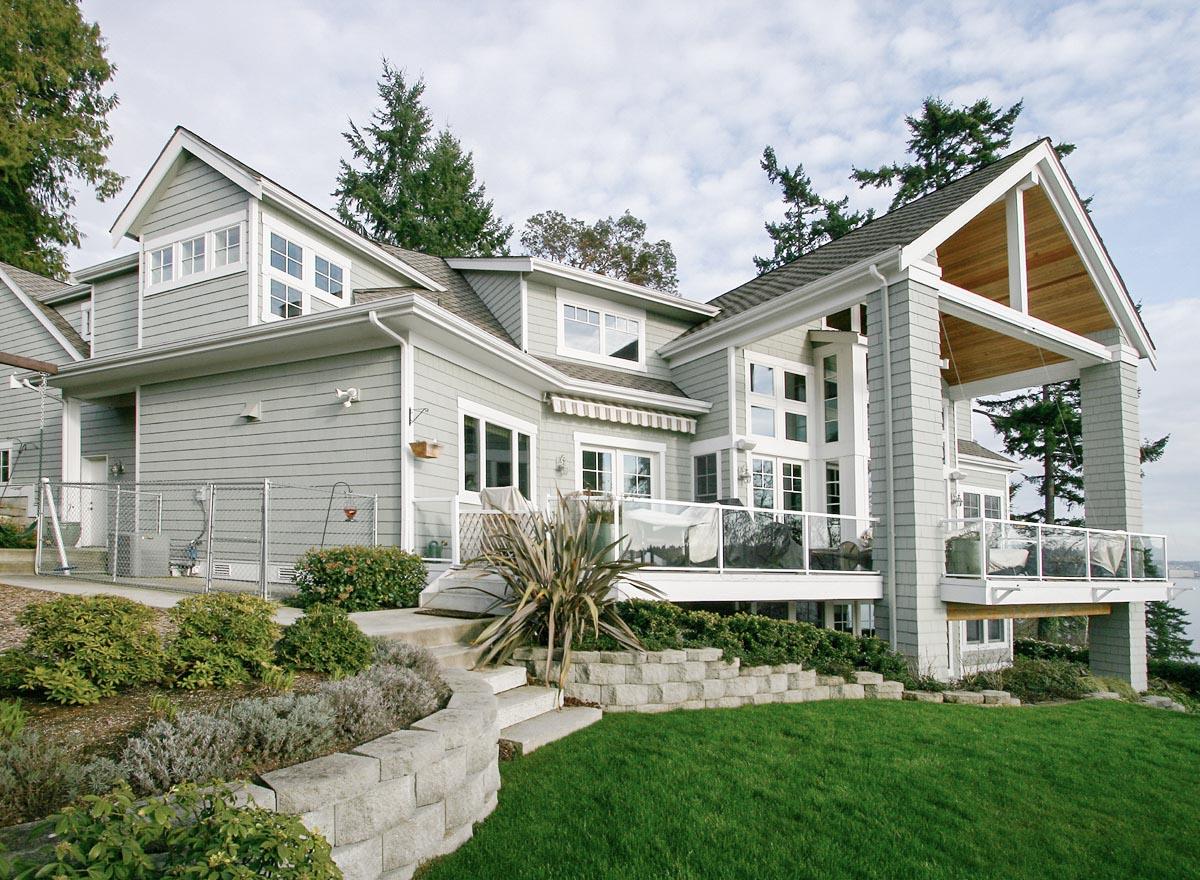 House plan exterior of a multi-story home with gables, dormers, large windows, and a covered outdoor living space.