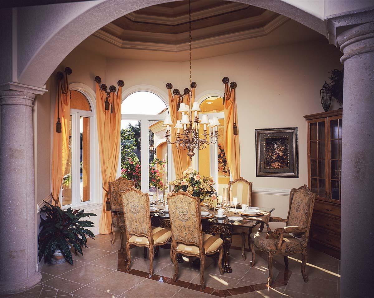 Formal dining room with arched windows, ornate chandelier, decorative table setting, and classic furnishings.